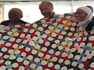 A quilter proudly shows off her work as Professor Lonnie Graham (c) and N.Y. Nathiri (r) assist with the display. January 25, 2013 (Photo credit: WONO)