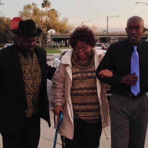 Dr. Charlie Jean Salters (c) being led by son, Clint Salters (r), as she make her way to speak at MLK Community March, March 5, 2014. Tinker Field, Orlando. (Photo: WONO)
